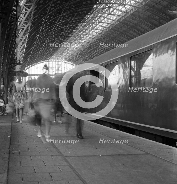 Travellers walking along a platform at Centraal Station, Amsterdam, Netherlands, 1963. Artist: Michael Walters