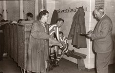Footballers adjust their boots in the locker room, 1953. Artist: Unknown