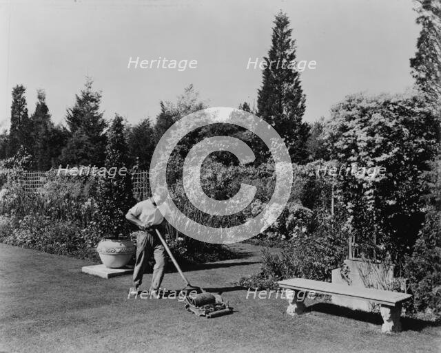 Gardener pushing lawn mower, posed to illustrate Rudyard Kipling's poem The Glory of the Garden,1917 Creator: Frances Benjamin Johnston.