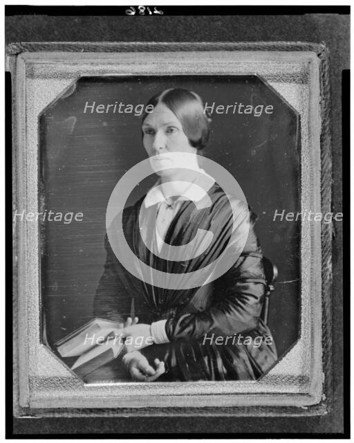 Unidentified woman, half-length portrait, facing left, seated holding book, between 1846 and 1856. Creator: Marcus Aurelius Root.