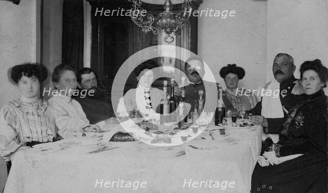 Fire Chief A. F. Domishkevich Sitting at a Table Set for a Holiday Together with..., early 20th cent Creator: Unknown.