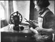 A glover or glove maker working at a sewing machine, Woodstock, Oxfordshire, 1920-40. Creator: George R Long.