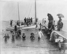 Men, women, and children in bathing suits on dock, sailboats, and in water..., c1880. Creator: Unknown.