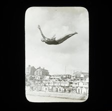 A swimmer diving into the sea at Southcliff, Walton-on-the-Naze, with beach huts on South..., 1920s. Creator: Norman Kingsley Harrison.