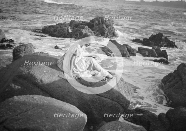 Wilson, Helen, Mrs., seated on rocks at the beach, between 1906 and 1928. Creator: Arnold Genthe.