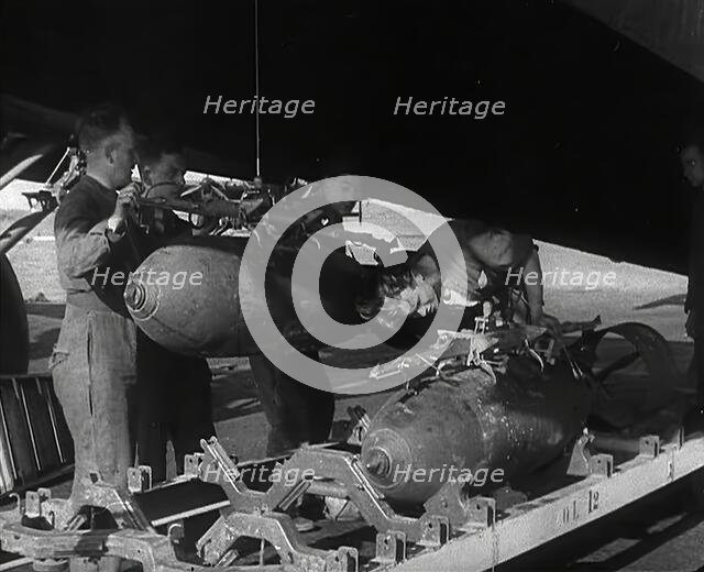 RAF Ground Crew Members Fixing Bombs to an Avro Lancaster Bomber, 1942. Creator: British Pathe Ltd.
