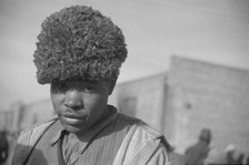 Negro with a fur cap, a flood refugee in the camp at Forrest City, Arkansas, 1937. Creator: Walker Evans.