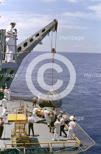 Gemini 5 capsule hoisted onboard recovery ship, 1965. Creator: NASA.