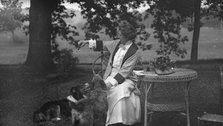 Tarbell, Ida, Miss, with dogs, seated outdoors, 1912 or 1913. Creator: Arnold Genthe.