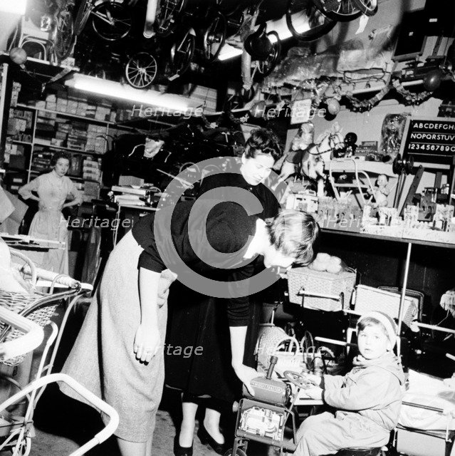 Child trying out a toy in a London toy store, c1950s. Artist: Henry Grant