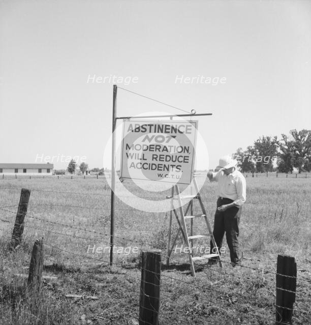 Member of the committee...erects sign on U.S. 99 highway, near Hanford, California, 1939. Creator: Dorothea Lange.