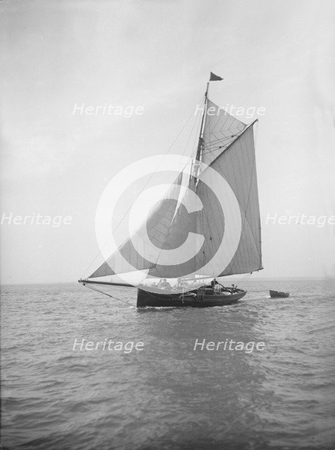 The cutter 'Citara' under sail and towing tender, 1911. Creator: Kirk & Sons of Cowes.