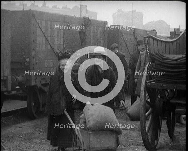 Two Elderly Female Civilians Wheeling a Barrow of Coal Away from a Railway Truck As Other..., 1924. Creator: British Pathe Ltd.