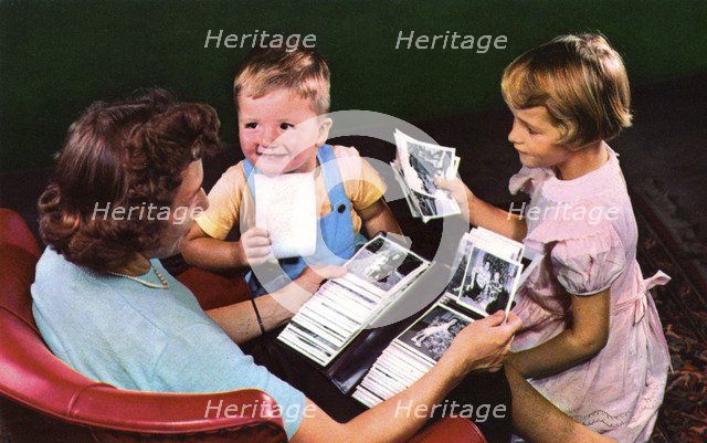 A mother and children looking at photos in a family album, Blackwood, New Jersey, USA, 1956. Artist: Unknown