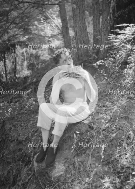 Man playing panpipes in the woods, between 1911 and 1942. Creator: Arnold Genthe.