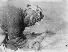 Blackfoot Indian fleshing a hide, c1927. Creator: Edward Sheriff Curtis.
