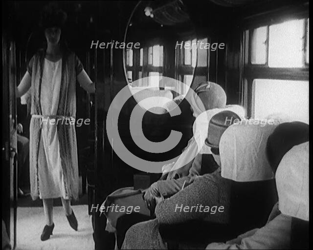 Female Civilian Wearing a Dress and Hat Modelling in Front of a Small Audience Inside a..., 1920. Creator: British Pathe Ltd.
