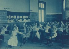 Children doing calisthenics while sitting at their desks in a classroom..., Washington, DC, (1899?). Creator: Frances Benjamin Johnston.