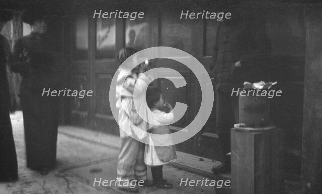 Two children standing on a sidewalk eating, Chinatown, San Francisco, between 1896 and 1906. Creator: Arnold Genthe.