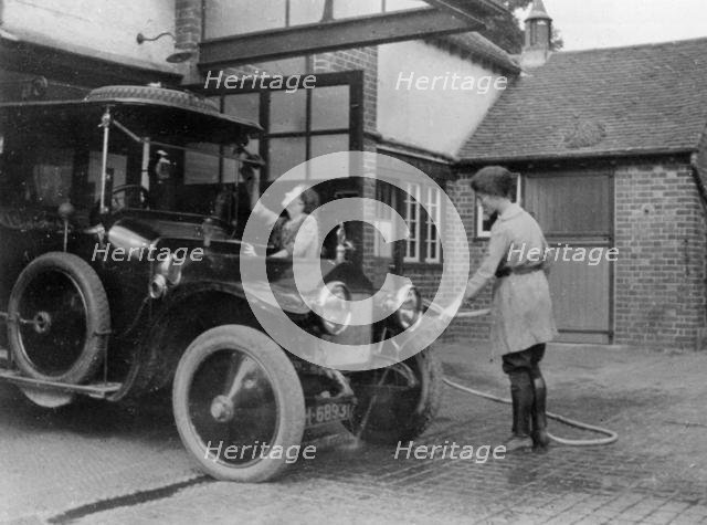 Chauffeuse washing car with hosepipe circa 1911. Creator: Unknown.