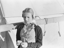 Young girl, migratory worker, beside the tent in which she lives, Kern County, California, 1938. Creator: Dorothea Lange.