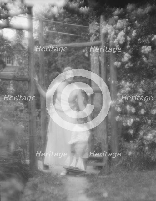 Conroy, Frank, Mrs., and child, standing by a garden gate, 1923 Creator: Arnold Genthe.
