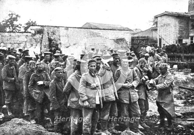 'Derriere L'ennemi refoule; Nos territoriaux distribuent du pain a des prisonniers...1915 (1924). Creator: Unknown.