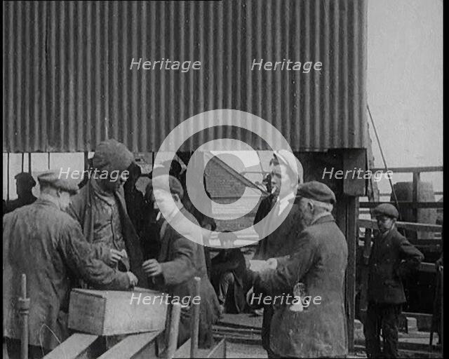 A Group of Miners Gathering and Smoking at a Pit Head, 1920. Creator: British Pathe Ltd.