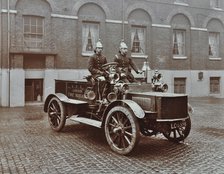 Firemen in brass helmets aboard a motor hose tender, London Fire Brigade Headquarters, London, 1909. Artist: Unknown.