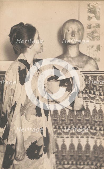 Woman wearing a kimono, standing, looking at a sculpted bust, c1900. Creator: Eva Watson-Schutze.