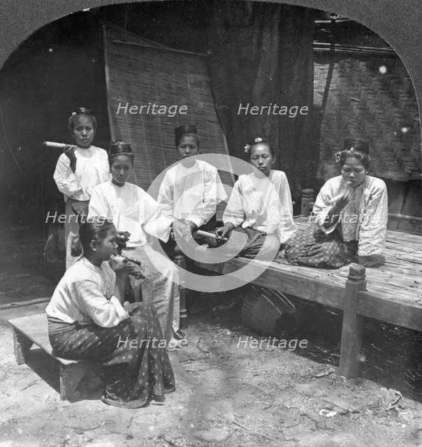 Burmese women smoking outside their home, Mandalay, Burma, 1908.  Artist: Stereo Travel Co