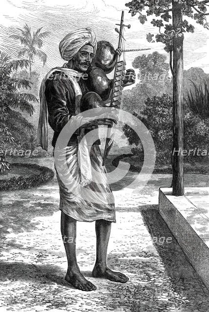 A strolling minstrel at Madras playing the tingadee, 1876. Creator: Unknown.