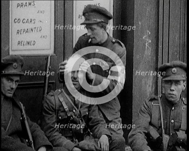 Irish Soldiers Sitting in the Street and Tending to Their Injuries from Fighting in Dublin, 1922. Creator: British Pathe Ltd.