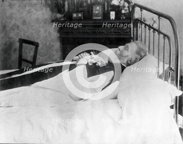 A dead man, wearing robes, lying on his deathbed, (1900?). Creator: Unknown.