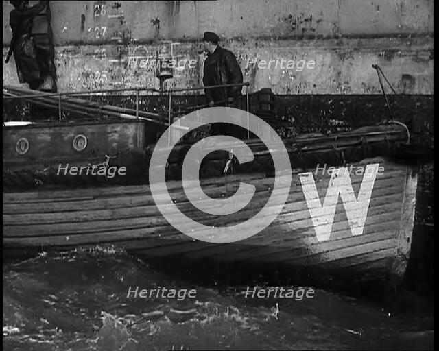 Small Wooden Customs Boat With Male Crew Member Standing at  the Bow End Alongside..., 1939. Creator: British Pathe Ltd.