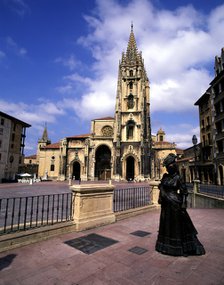 Exterior view of the Cathedral of Oviedo with the sculpture of a lady in the foreground.