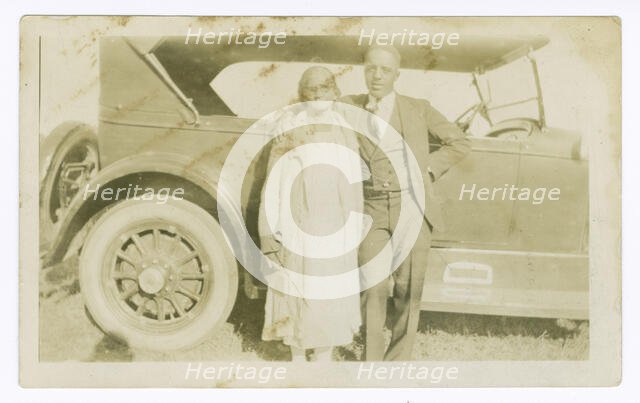 Photograph of a man and woman in front of car, ca. 1921. Creator: Unknown.