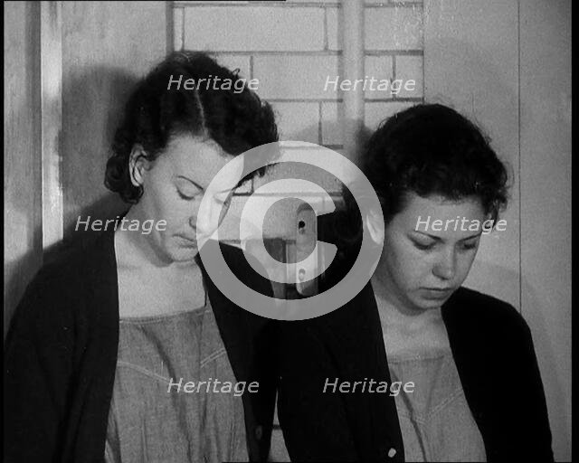 American Female Civilians Wearing Prisoners Outfits Standing Against a Wall in a Prison, 1930. Creator: British Pathe Ltd.
