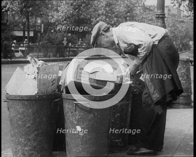 Male American Civilian Hunting Through a Rubbish Bin, 1930. Creator: British Pathe Ltd.