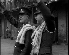 Two Uniformed British Soldiers With Arms Raised Standing Outside Brick Building, 1937. Creator: British Pathe Ltd.