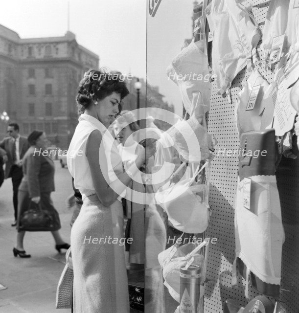 A young woman looking in the window of a lingerie shop in Piccadilly Circus, London, c1946-c1959. Artist: John Gay
