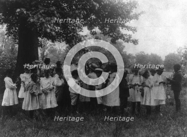 African American school children and teacher, studying leaves out of doors, (1899?). Creator: Frances Benjamin Johnston.