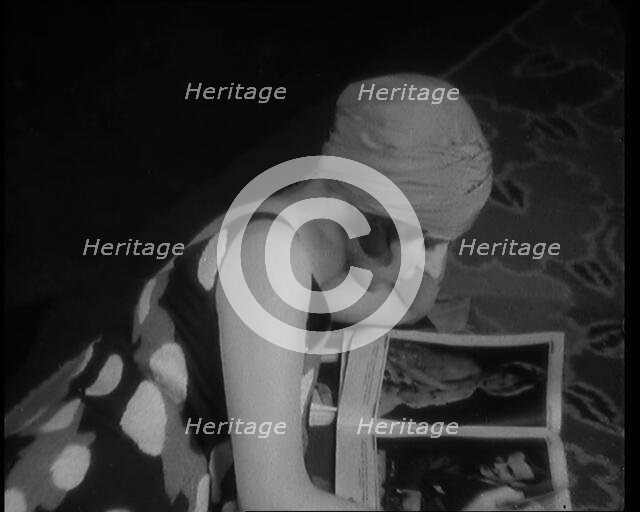 Female Civilian Laying on a Carpet Wearing a Swimsuit and Sandals Reading a Magazine, 1920. Creator: British Pathe Ltd.