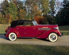 A 1936 Auburn 852 car on a gravel driveway in the autumn sunlight. Artist: Unknown