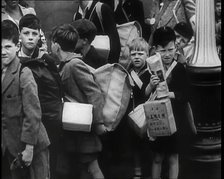 British Child Evacuees Standing on a Pavement With Bags and Boxes as Adults are Standing..., 1939. Creator: British Pathe Ltd.