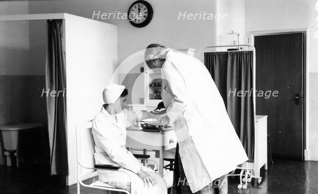 The Rowntree doctor examines the arm of a member of staff, Rowntree Factory, York, Yorkshire, 1953. Artist: Unknown