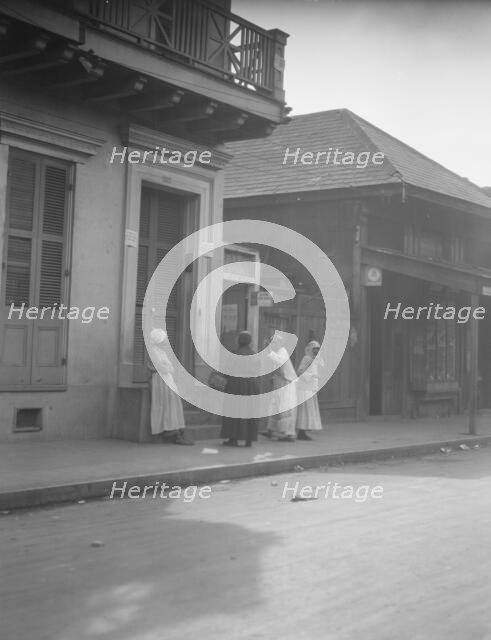 View from across street of four women talking, New Orleans, between 1920 and 1926. Creator: Arnold Genthe.