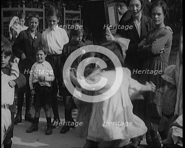 A Group of Civilian Children Dancing in Front of a Hurdy Gurdy Watched by a Small Crowd, 1920. Creator: British Pathe Ltd.