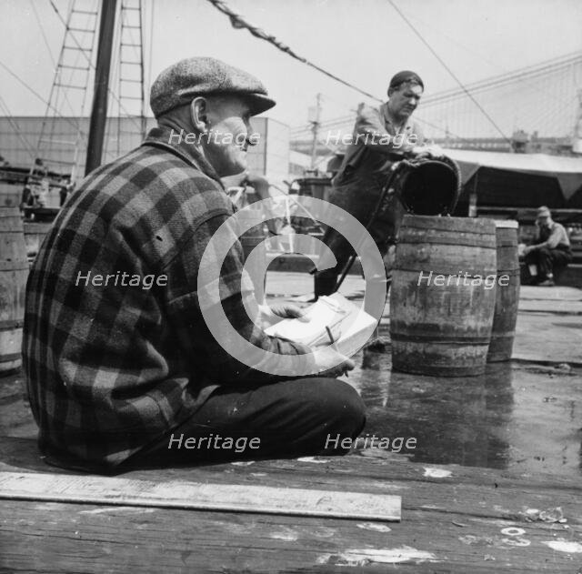 New England fisherman checking baskets of fish as they are lifted from his ship, New York, 1943. Creator: Gordon Parks.