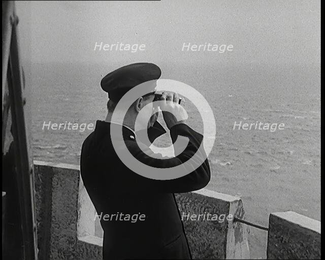 Lighthouse Keeper Looking Through Binoculars at the Turbulent Sea, 1920s. Creator: British Pathe Ltd.